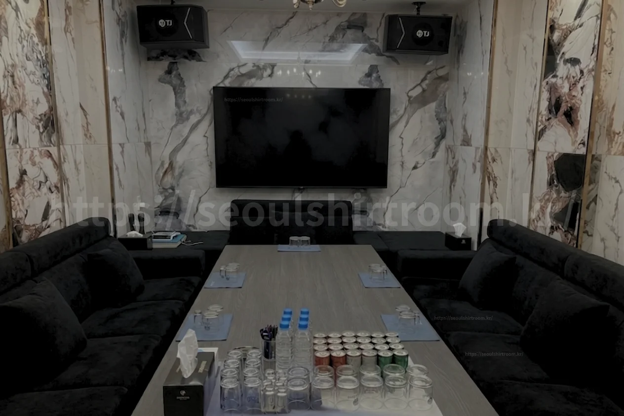 신림셔츠룸 대형 테이블과 블랙 소파, 모니터가 설치된 대형룸 내부
